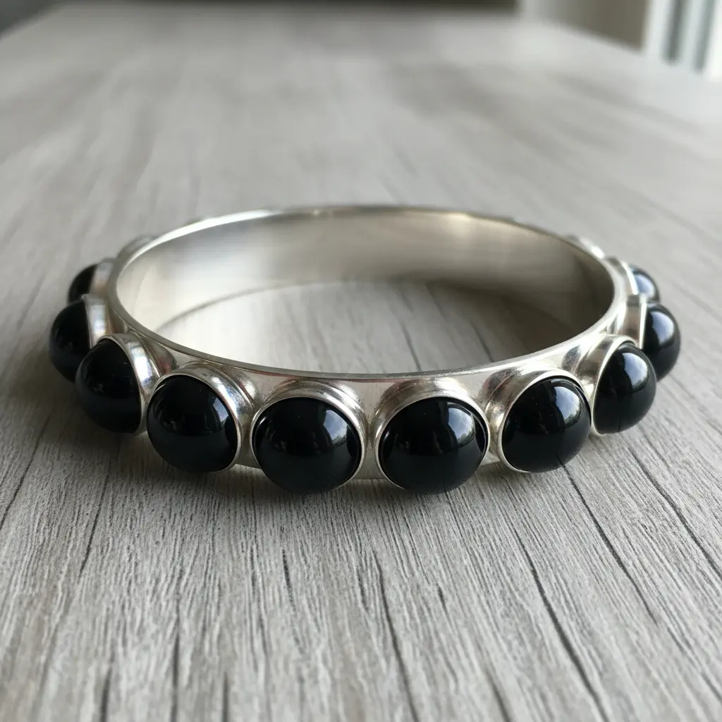 A polished silver bangle blank with several glossy, spherical black onyx beads evenly spaced along the top.