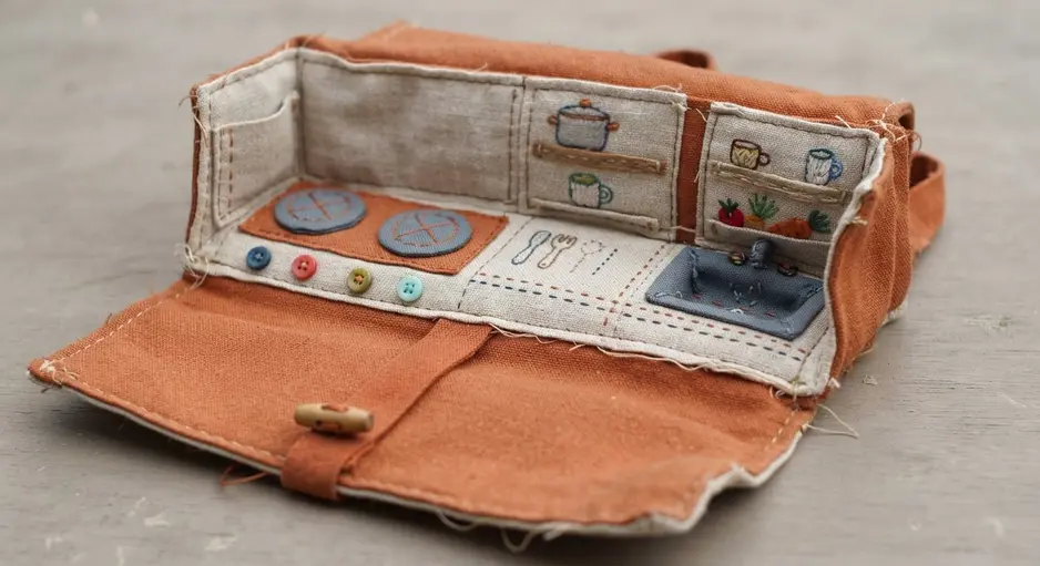 A piece of burlap canvas rolled out to reveal a sewn-on doll kitchenette with fabric appliances.