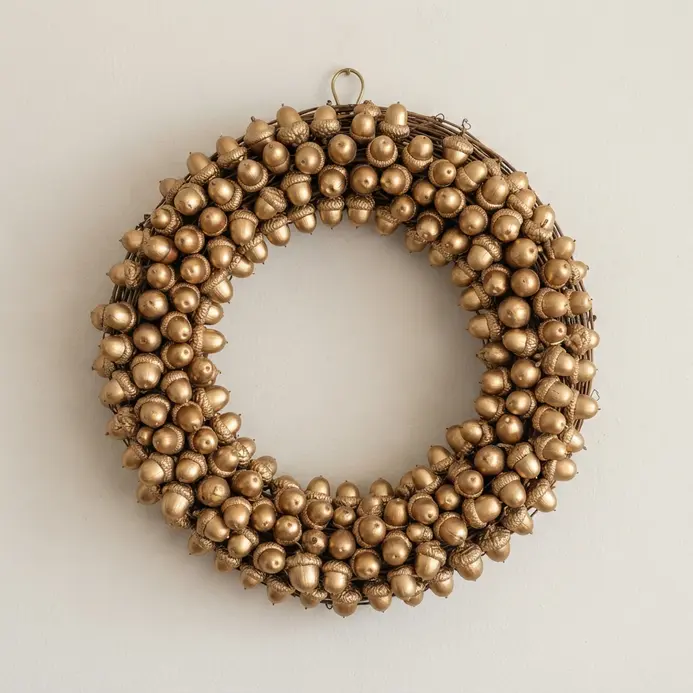 A circular wreath featuring natural and gold-dipped acorns clustered on a rustic vine base.
