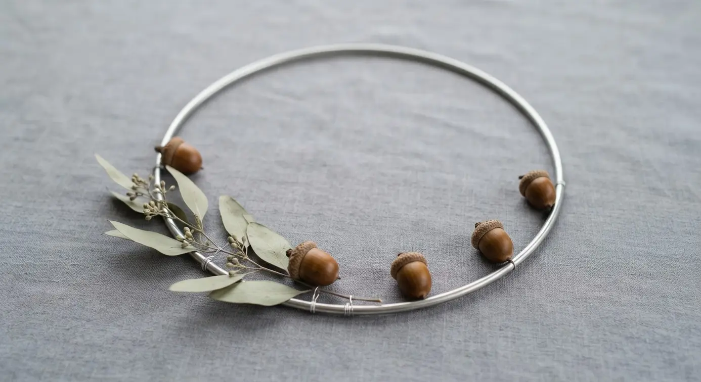 Sleek metal embroidery hoop holding a few carefully placed acorns and a sprig of eucalyptus.