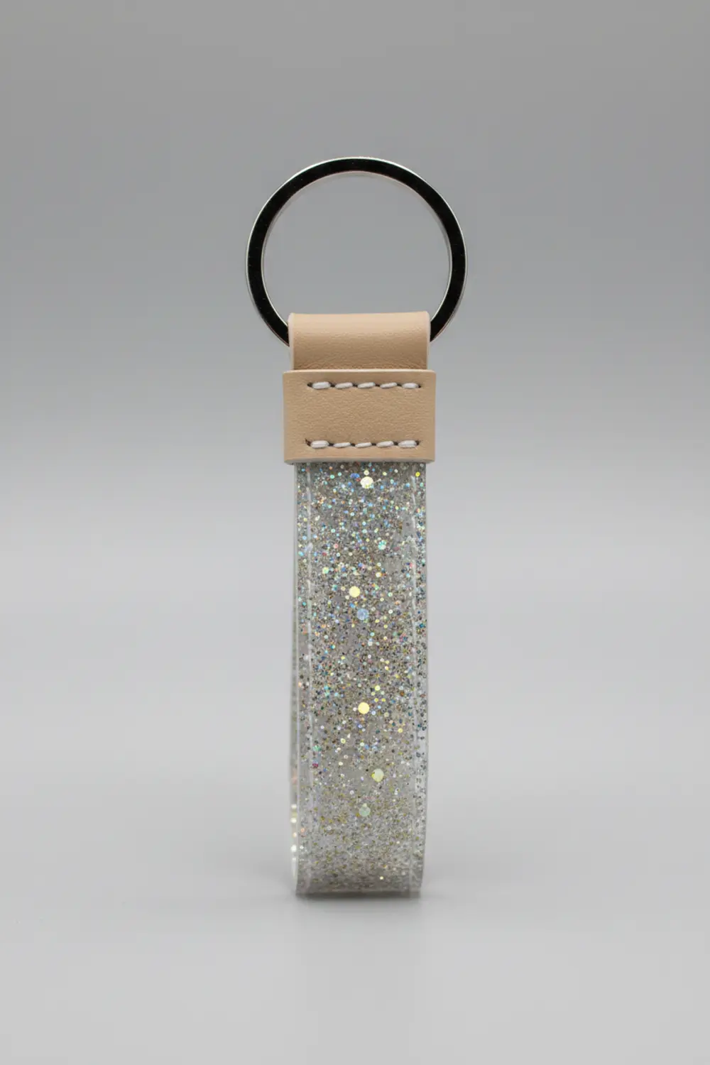 A small, rectangular keychain with a folded tab, crafted from silver glitter faux leather with a metal key ring.