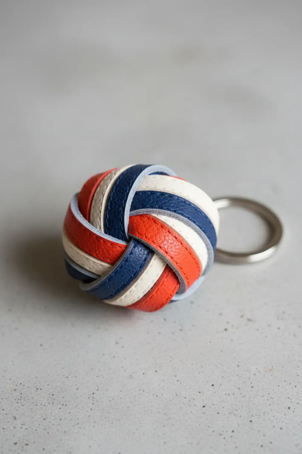 A keychain made from interwoven strips of black and white faux leather, knotted together in a striped pattern.