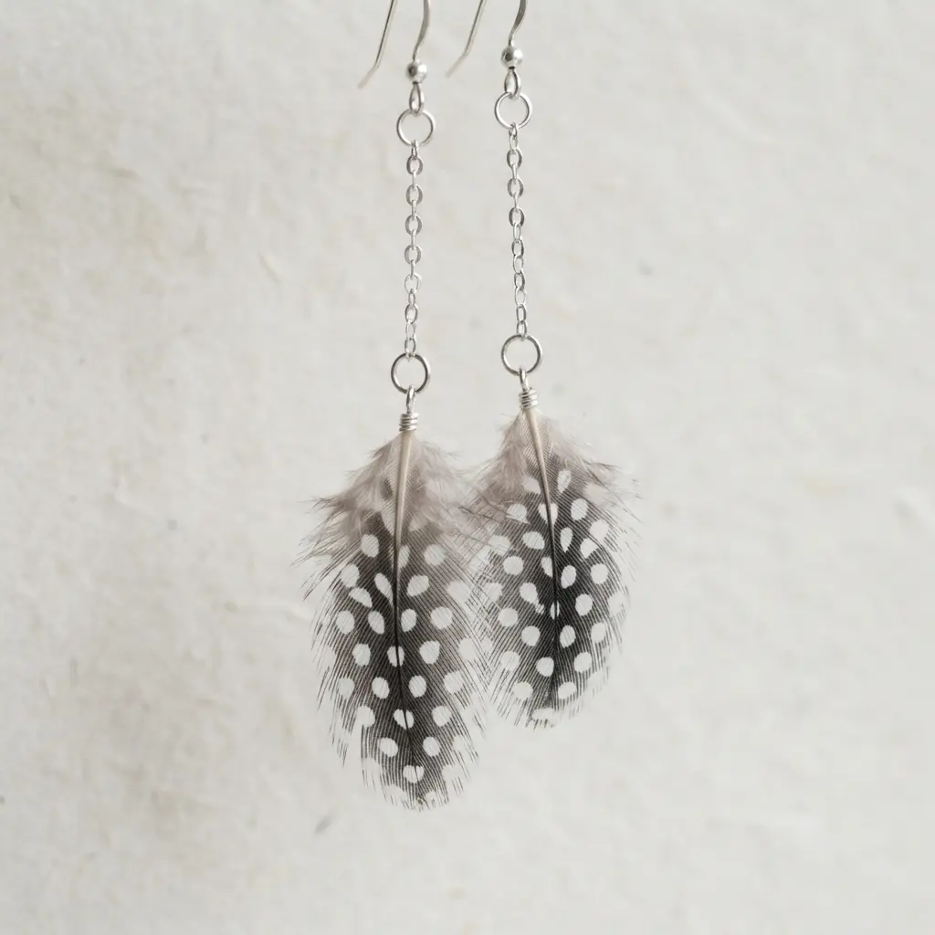 A small, white feather with black polka dots dangling from a delicate silver chain.