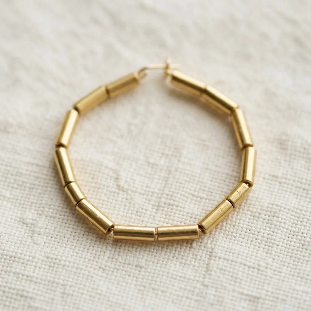 Contemporary gold hoop earrings constructed with straight, gold tube beads arranged to form a segmented geometric shape.