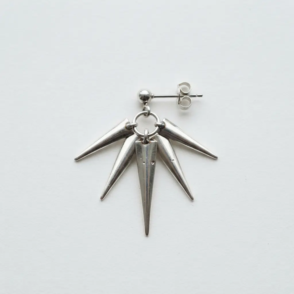 A dramatic earring featuring three silver spikes of different lengths arranged in a fan shape.