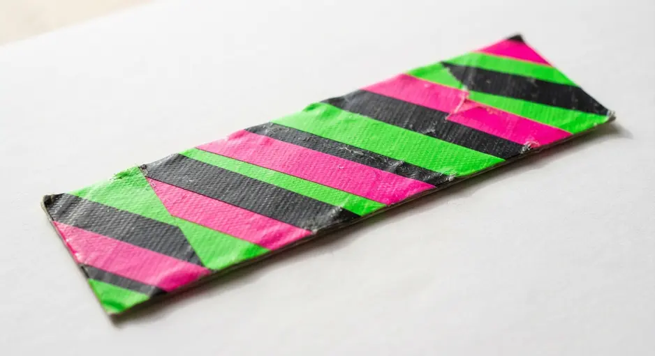 A durable, laminated bookmark made from two layers of neon striped duct tape, peeking out from a book.
