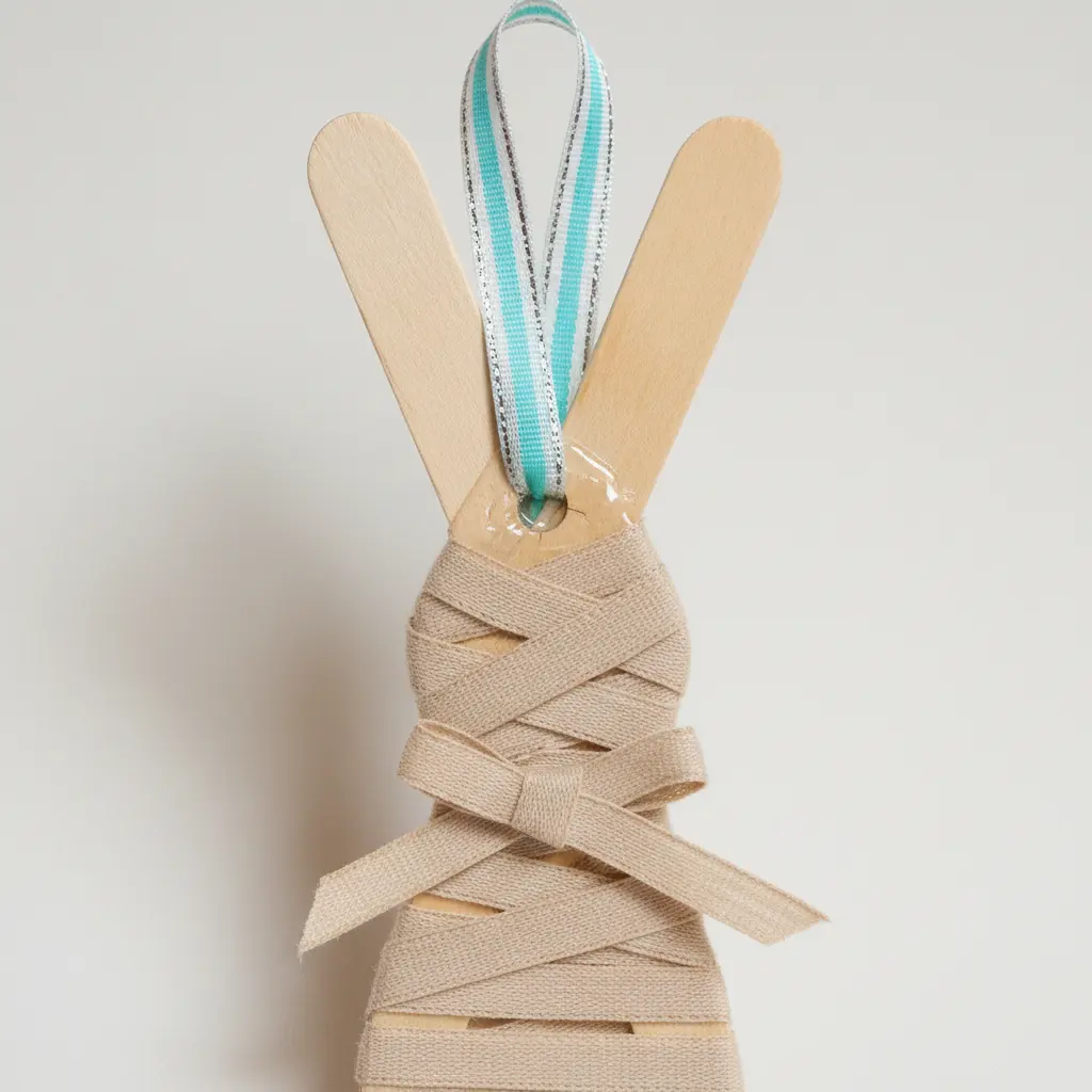 A finished popsicle stick bunny with a pastel ribbon loop glued to the back for hanging.