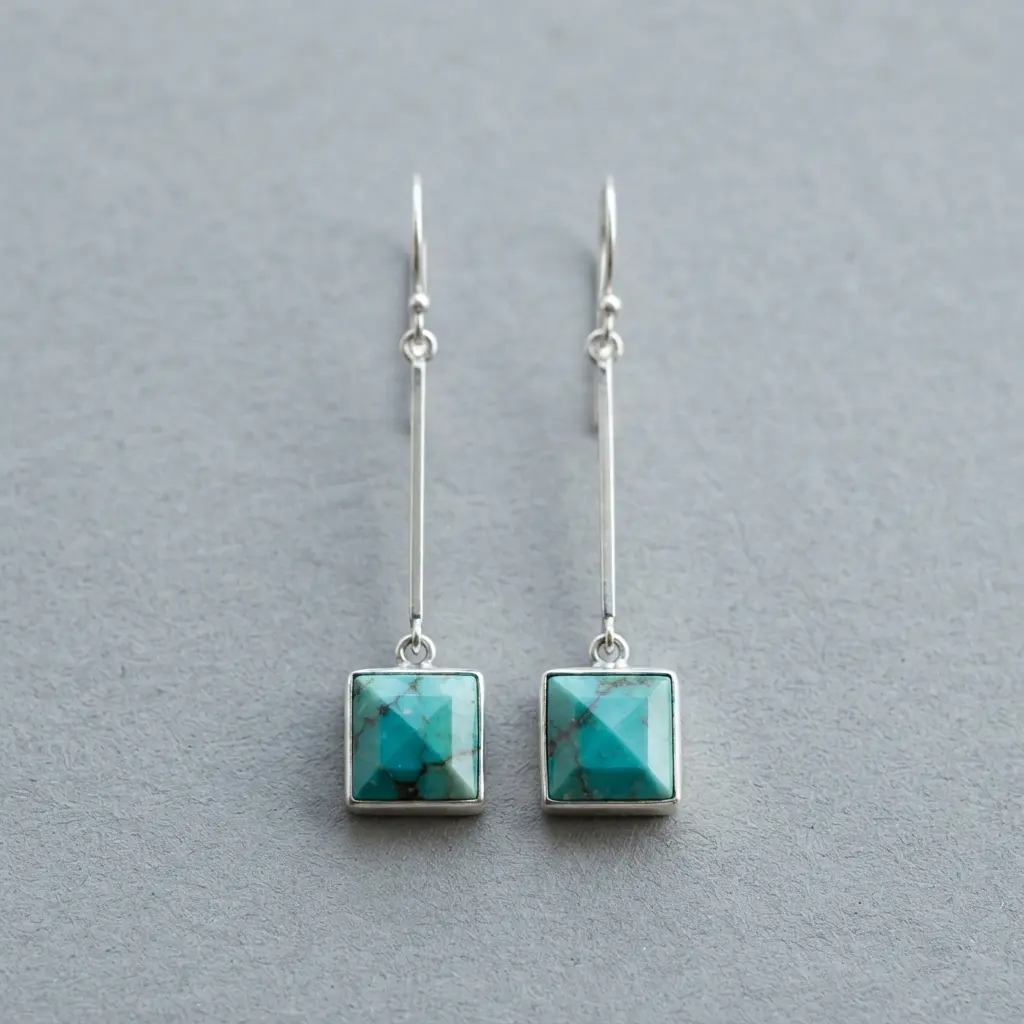 A pair of modern geometric earrings featuring square-cut turquoise stones suspended from a thin silver bar.