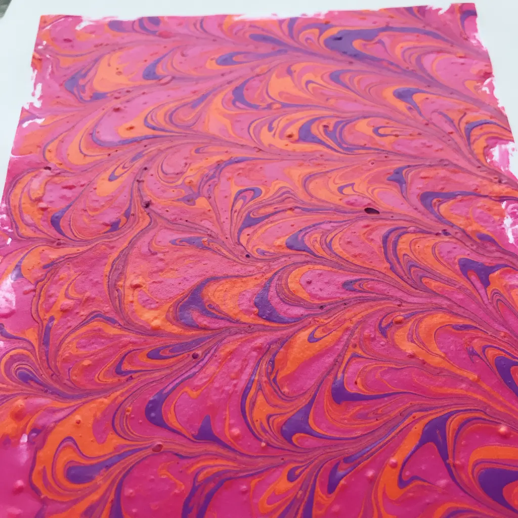 A sheet of paper with a swirled marbled pattern in vivid pink, orange, and purple.