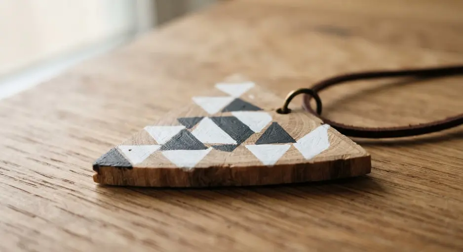 A sleek wooden pendant with a black and white geometric triangle pattern.
