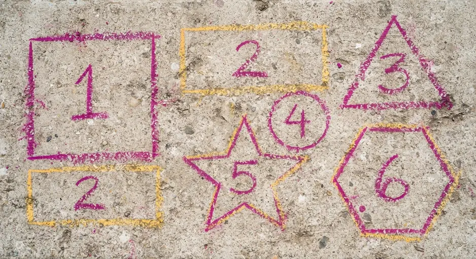 A colorful hopscotch course on a driveway, with numbered squares, circles, and triangles drawn in pink and yellow chalk.
