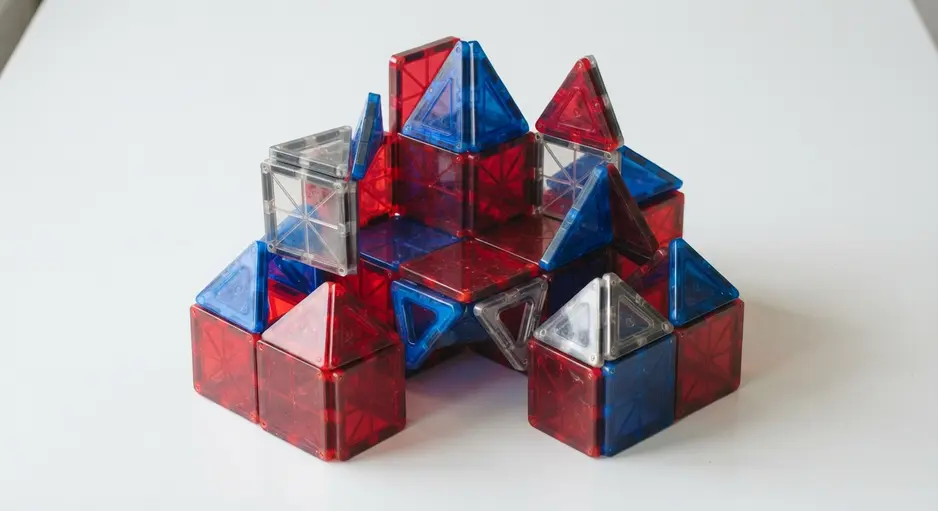 A simple three-dimensional cube structure built by a child using red and blue magnetic square tiles on a whiteboard.