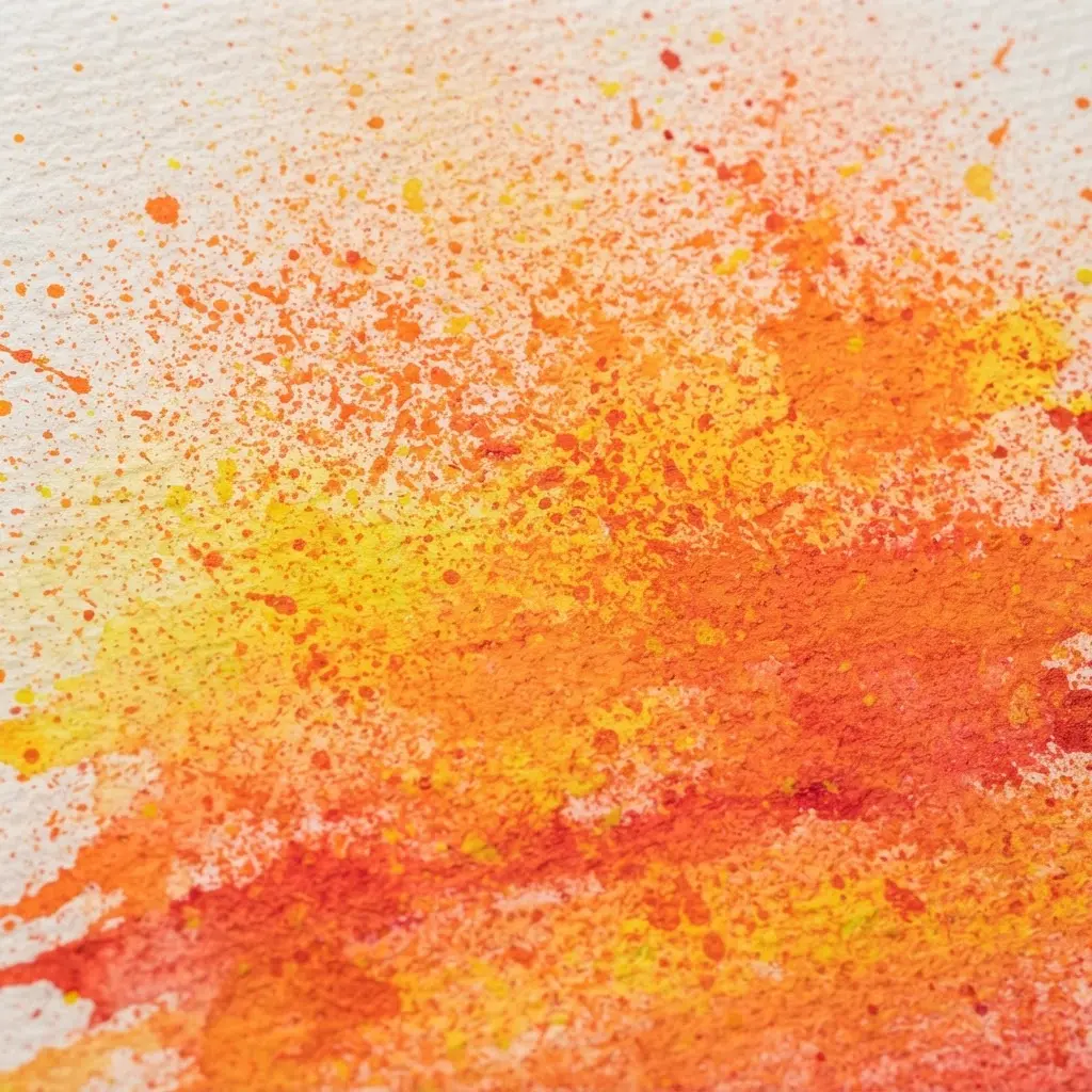 White paper featuring a bright orange and yellow sunset scene created with fine toothbrush paint mist.