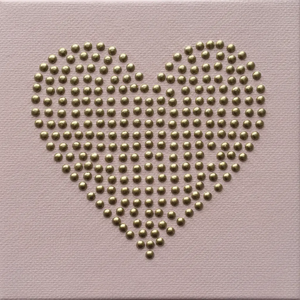 A delicate heart shaped like lace, created with tiny gold rivets on a blush pink canvas.