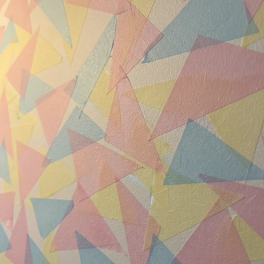 Pastel pink, blue, and yellow washi tape triangles overlapping on a light wall, creating a soft geometric cluster.