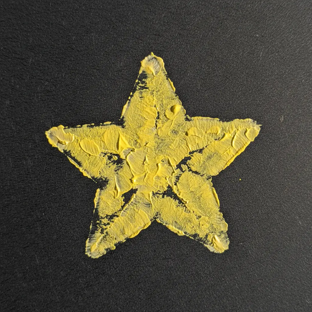 A potato half carved into a five-pointed star, stamped with yellow paint on dark paper, leaving a solid star shape.