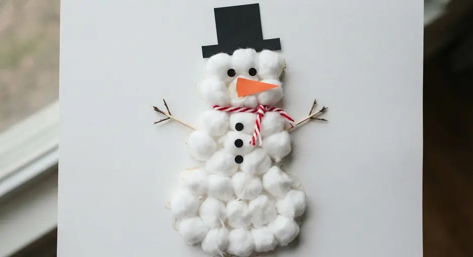 A simple snowman collage made from construction paper with cotton balls glued on for a textured body.