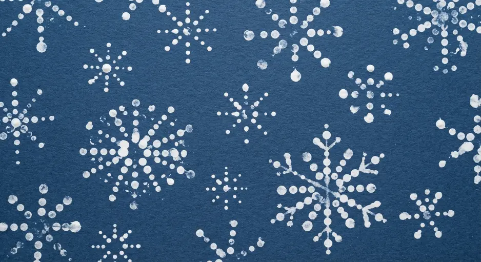 A symmetrical snowflake design stamped with white paint using the ends of Q-tips on dark paper.
